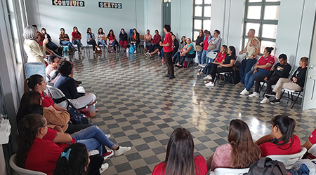 Se muestra grupo de personas sentadas reunidas en circulo